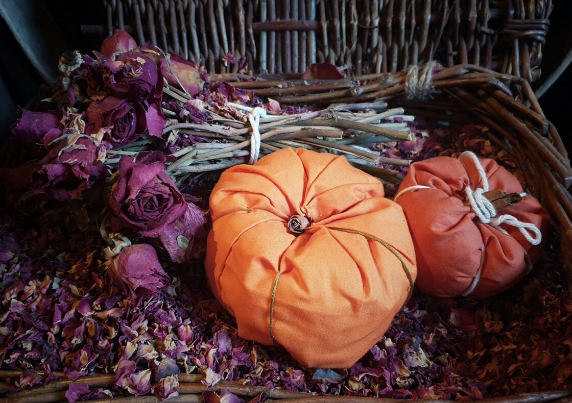 Two pomanders sit in a basket of dead rose petals