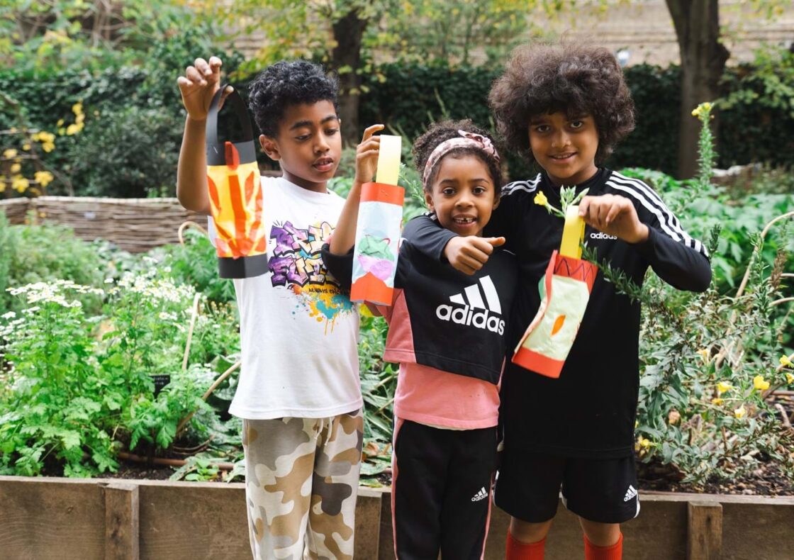 Three children hold up their handmade lanterns