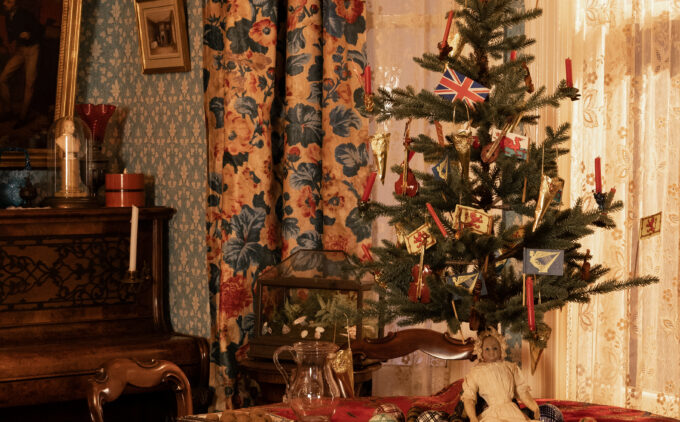 A table with small Christmas tree, dolls, and baubles.