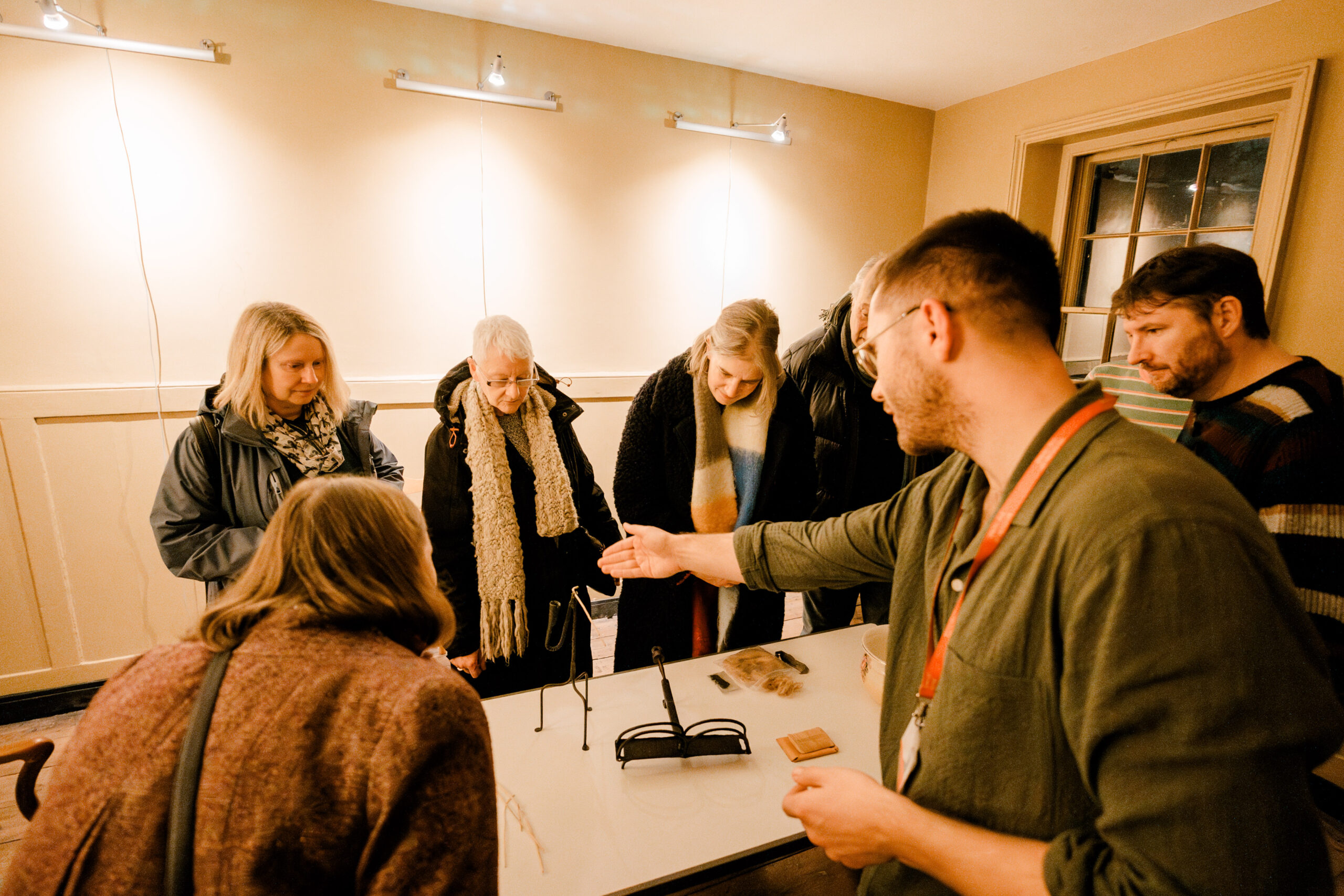 A group of people standing around a table with a curator gesturing at historical objects