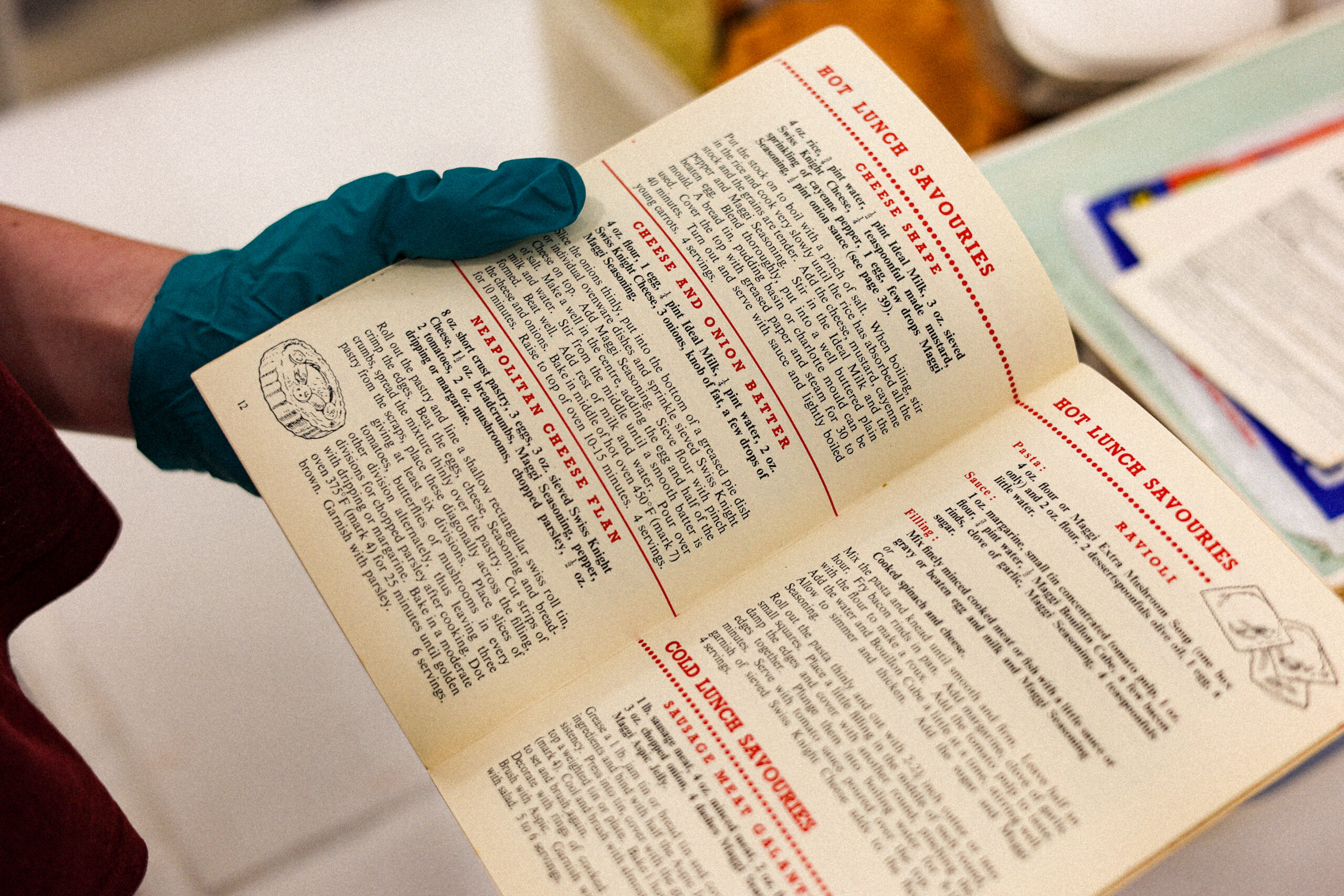 A gloved hand holds a book open with care