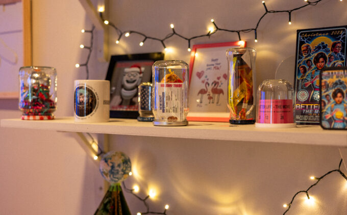 A close up view of a shelf with different items and frames decorated with Christmas lights.