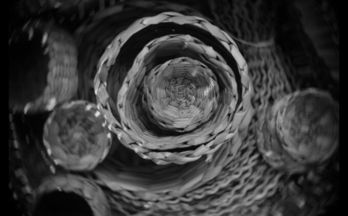A black and white photography of circular rush baskets, some inside of bigger ones, others next to each other.