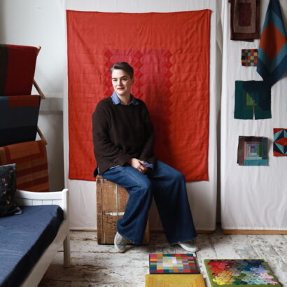 A portrait of Catherine-Marie Longtin in front of a red quilt.