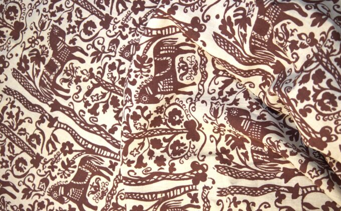 A close up photograph of a curtain with a repeated purple horse print alongside floral and folk motifs