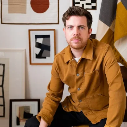 A portrait of Julius Arthur on a backdrop of framed prints displayed on a wall.