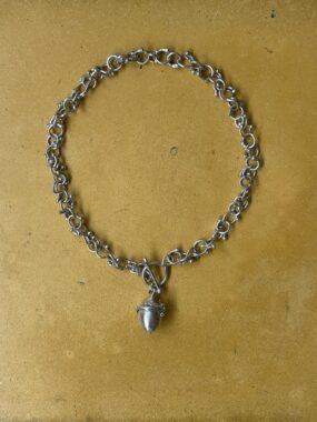 A silver bracelet chain on a gold-yellow background