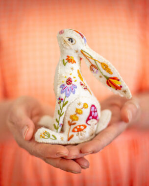Two palms holding an embroidered hare