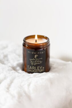 A burning candle, with the label on the jar reading 'midwinter'