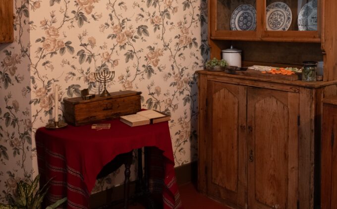 Close up view of a cabinet against floral wallpaper. There is a menorah on the wooden unit.