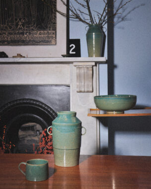 A selection of teal ceramics displayed by a fireplace.
